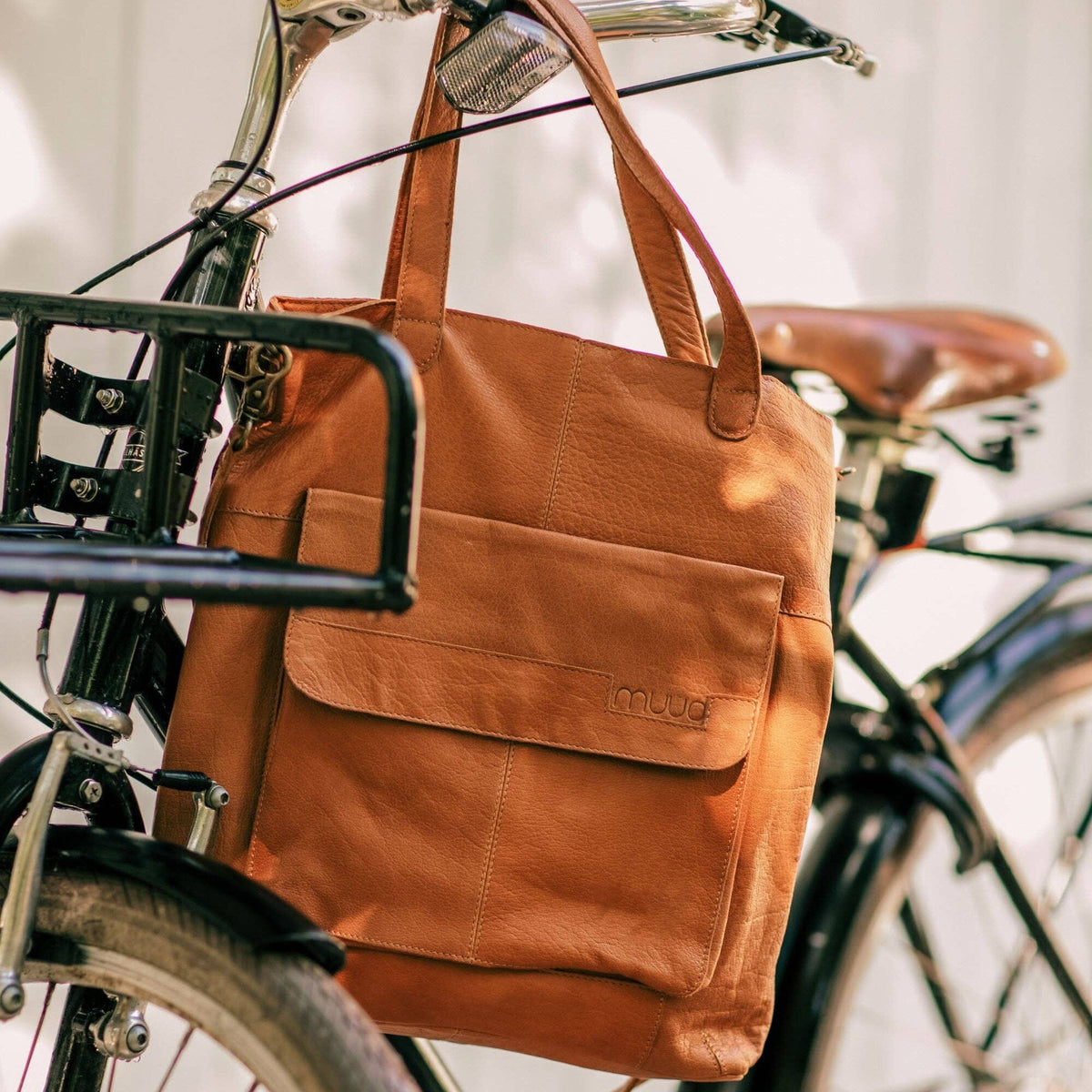 Brown leather bag attached to a bicycle with a blurred background