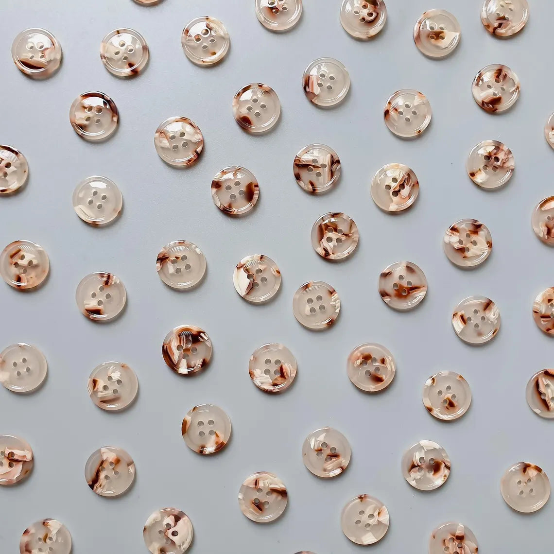 Pattern of rose gold buttons on a light blue background