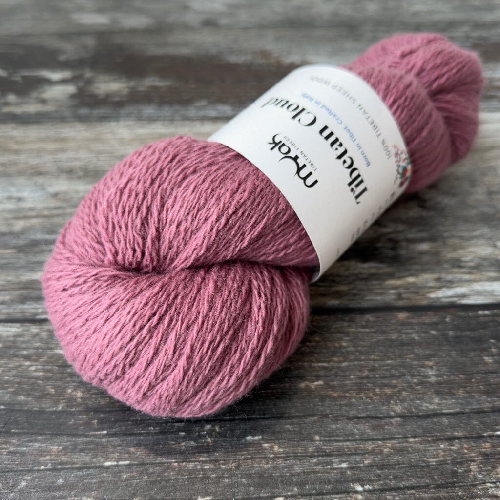 Pink skein of yarn with a label on a wooden surface