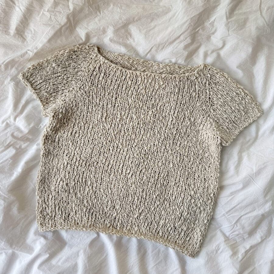 Knitted beige top on a white fabric background