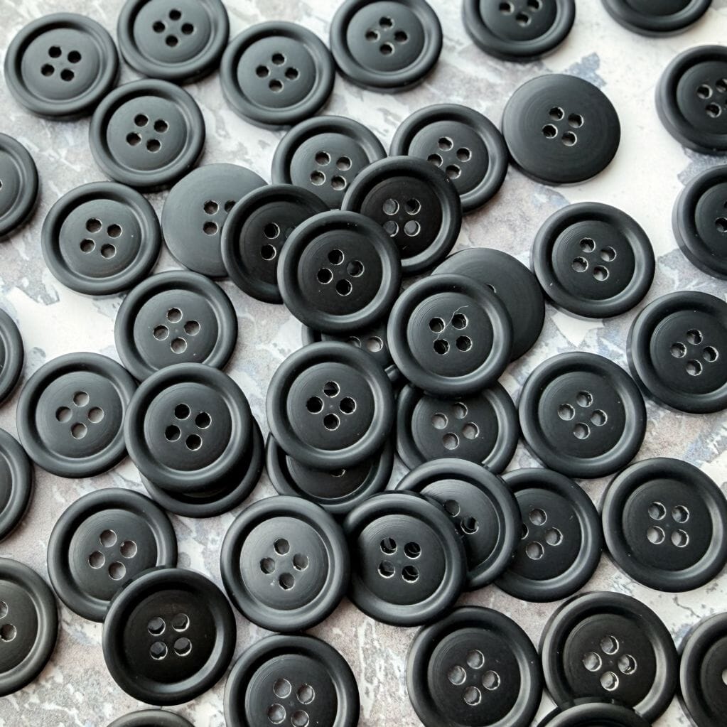 Pile of black buttons on a textured surface