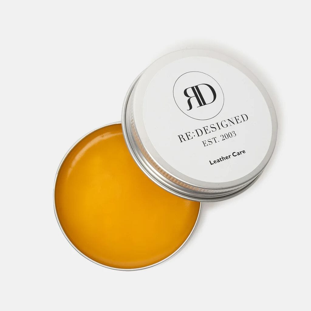 Yellow leather care balm in a white container with 'Re:Designed' branding on a light gray background