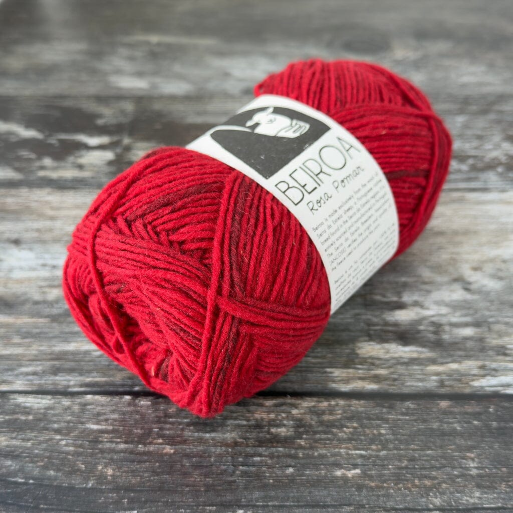 red ball of yarn on wooden surface with label beiroa