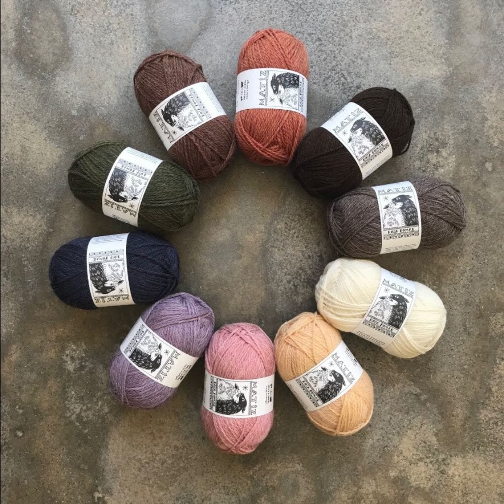 Assorted balls of yarn arranged in a circle on a textured surface