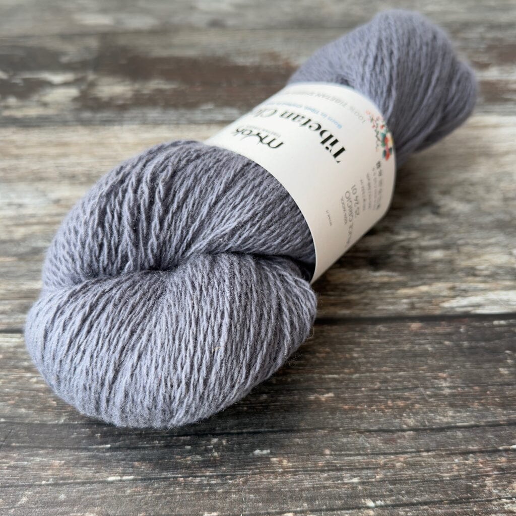 Gray skein of yarn with a label on a wooden surface