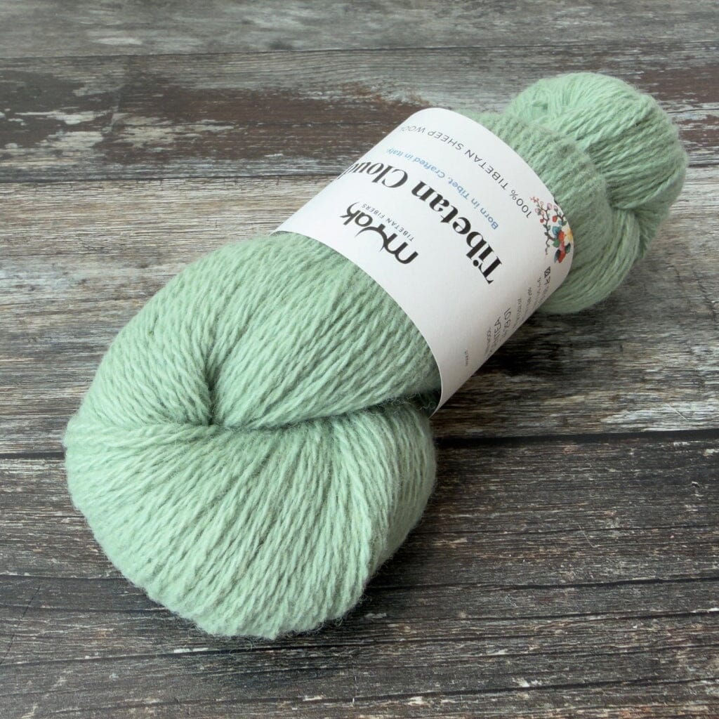 Light green skein of yarn with a label on a wooden surface