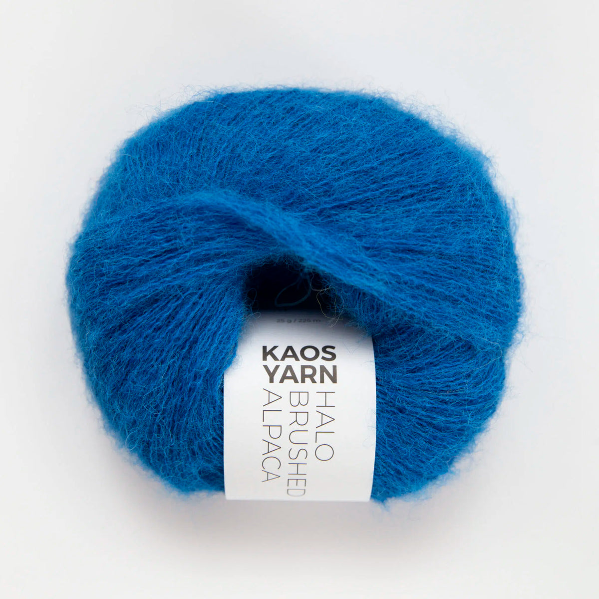 A single ball of bright blue mohair alpaca yarn with a white paper label reading 'KAOS YARN HALO BRUSHED ALPACA', photographed on a clean white background.