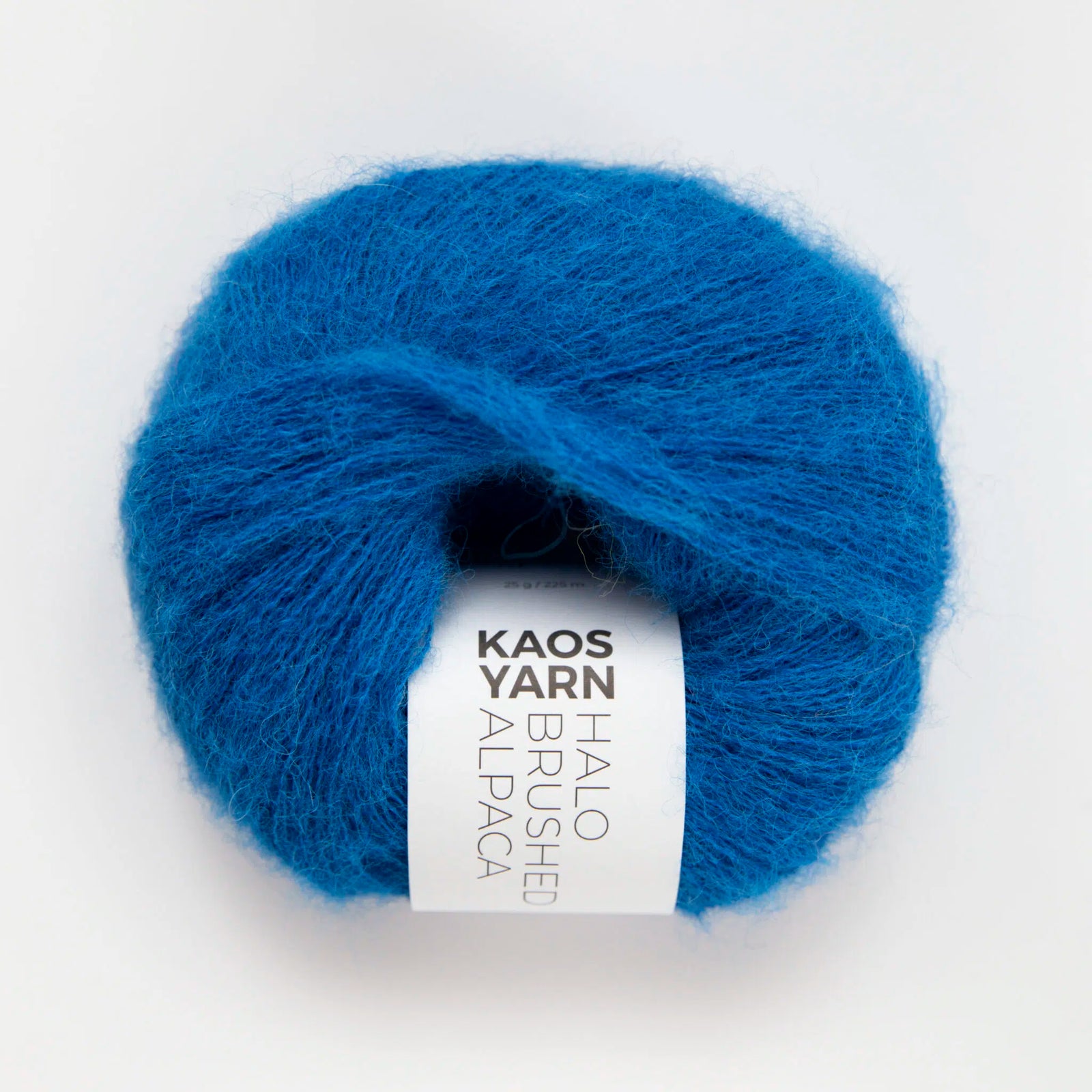 A single ball of bright blue mohair alpaca yarn with a white paper label reading 'KAOS YARN HALO BRUSHED ALPACA', photographed on a clean white background.