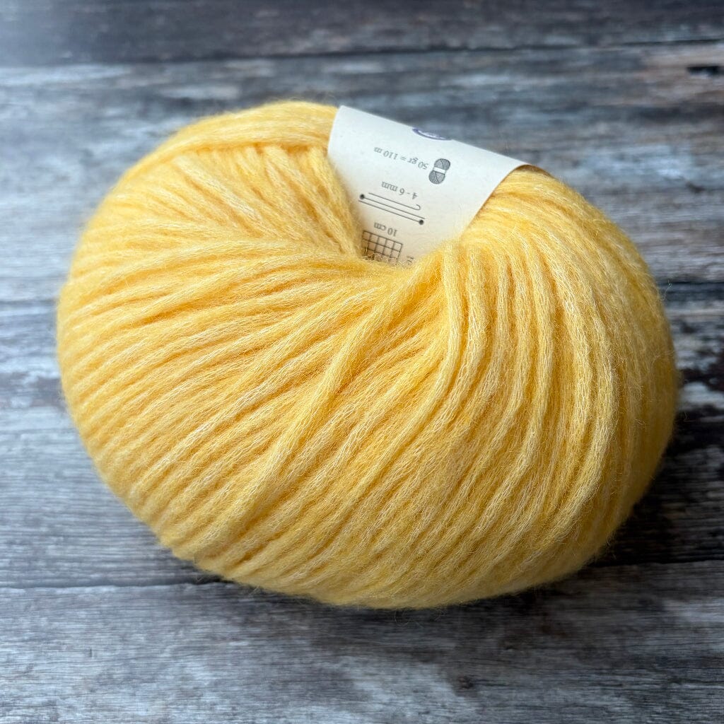 yellow ball of knitting yarn on wooden surface