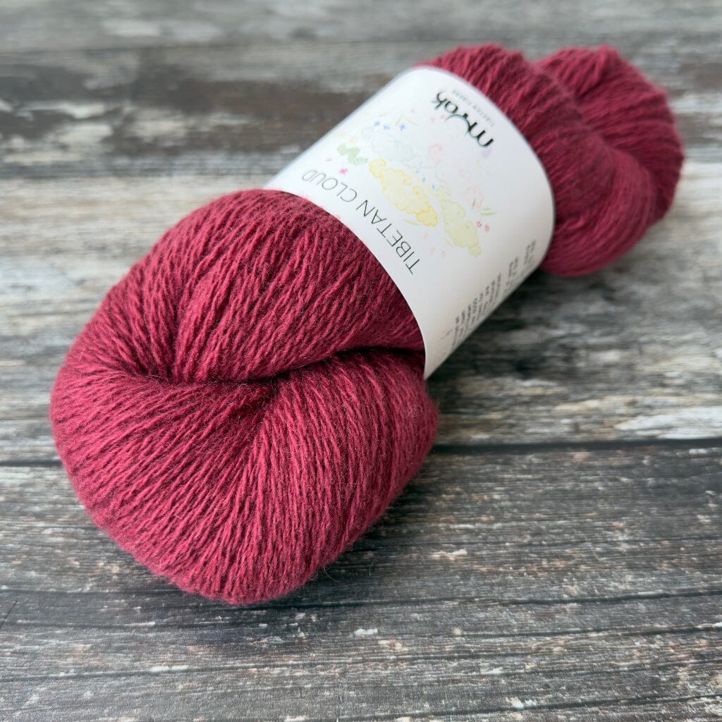 Red skein of yarn with a label on a wooden surface