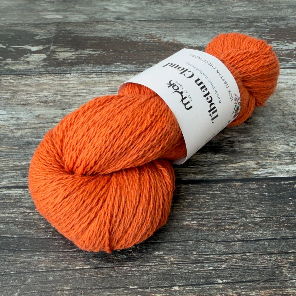 Orange yarn skein with a label on a wooden surface