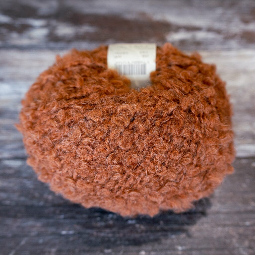 brown boucle yarn on wooden surface