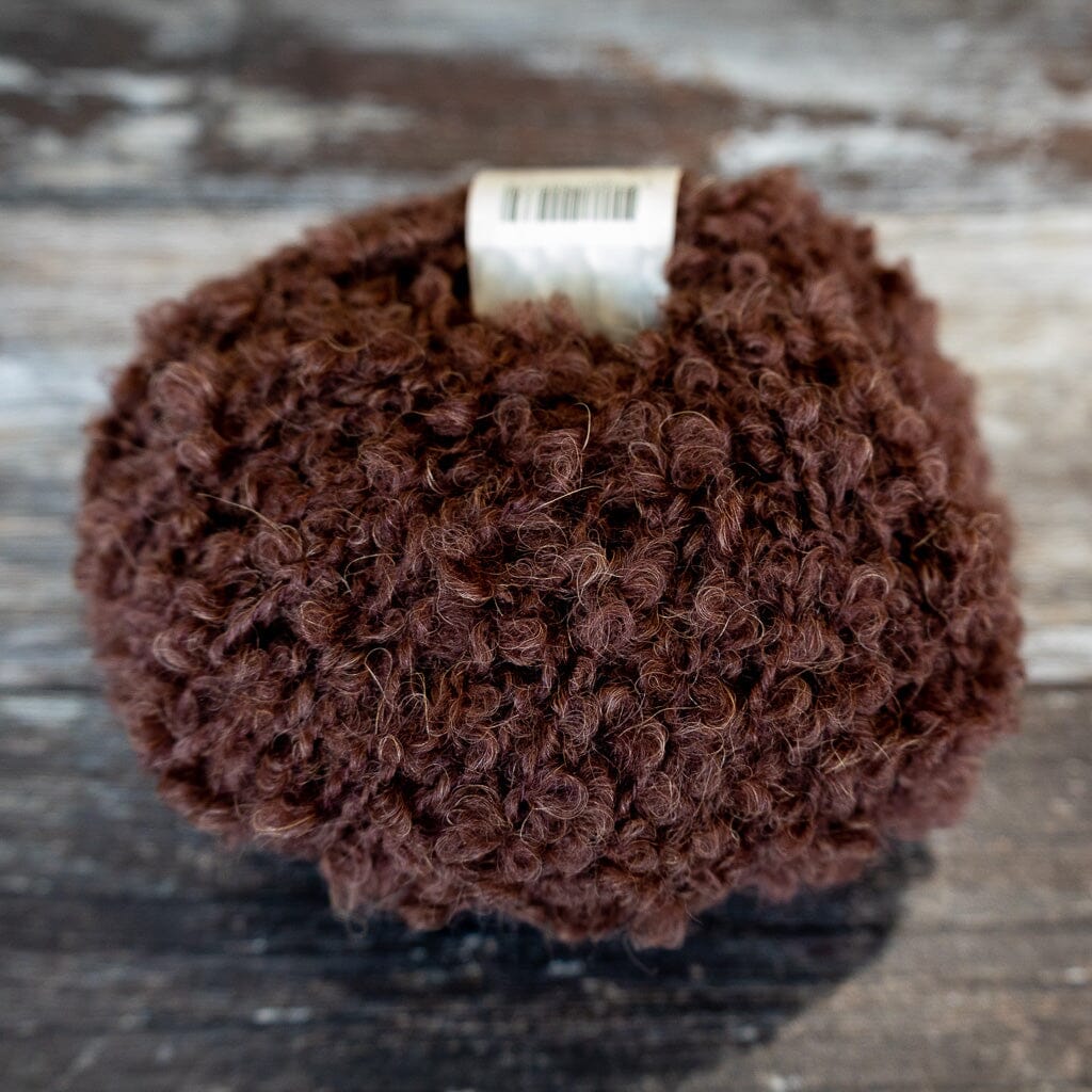 dark brown boucle yarn on wooden surface