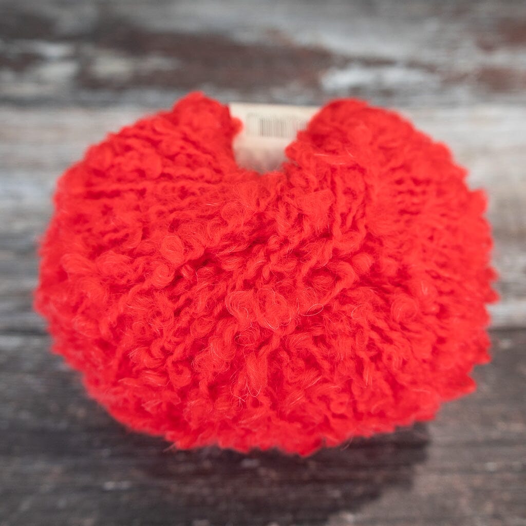 red boucle yarn on wooden surface