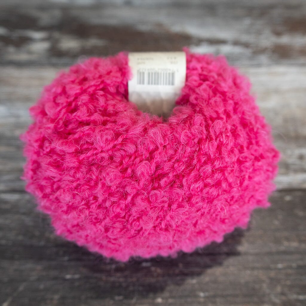 Pink boucle yarn on wooden surface