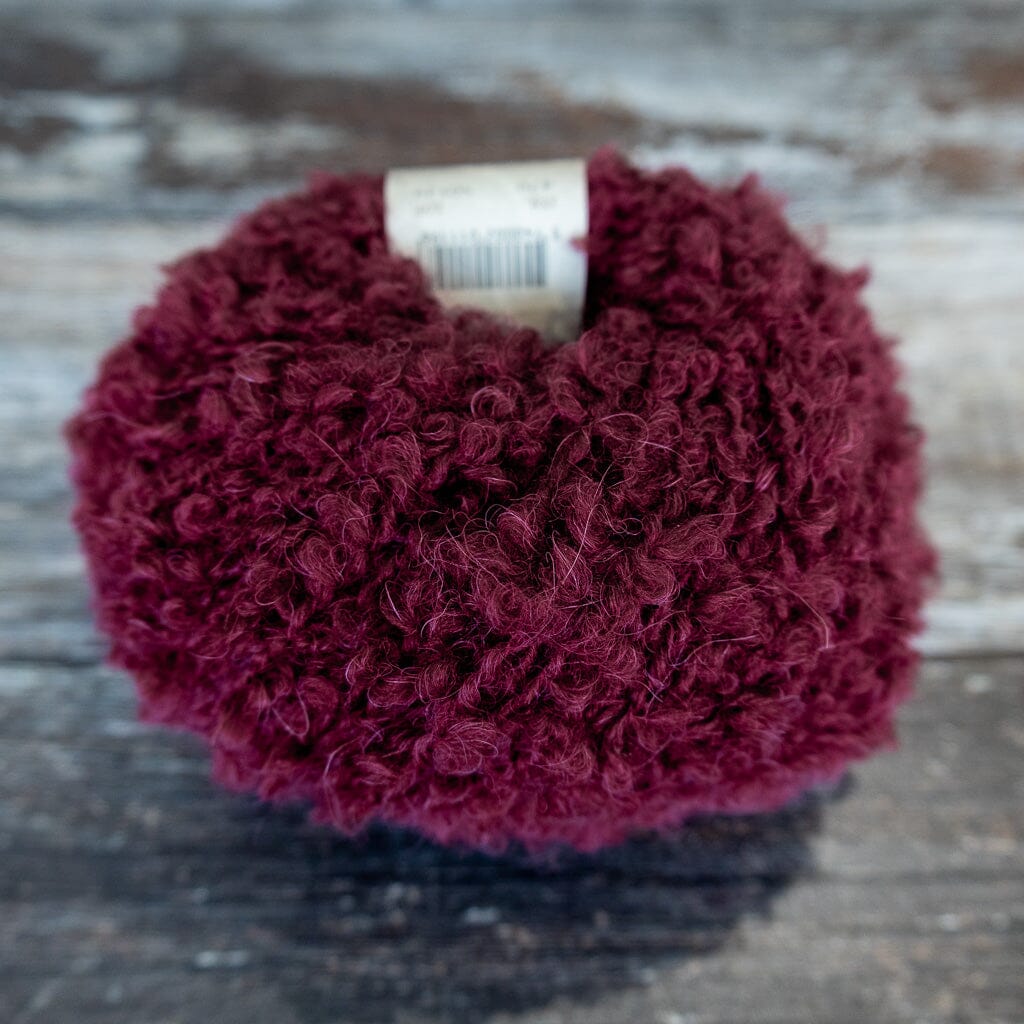 burgundy boucle yarn on wooden surface