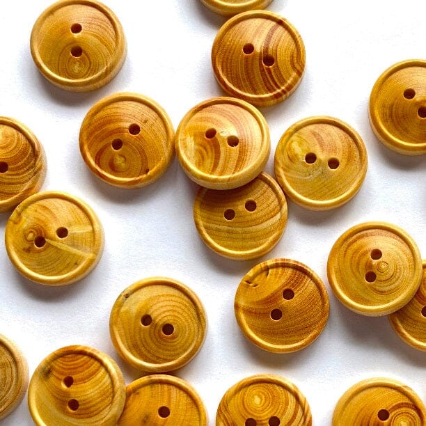 A close-up arrangement of round wooden buttons with visible grain patterns in warm golden-brown tones on a white background.