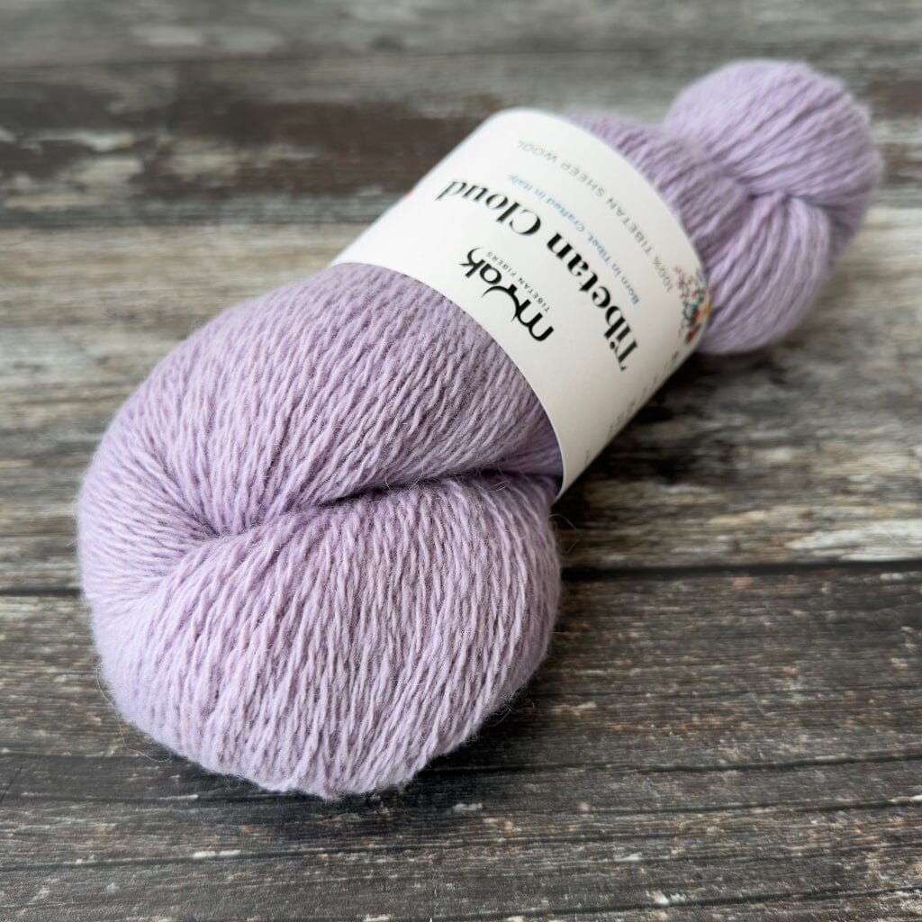 Ball of lilac yarn with a label on a wooden surface